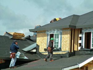 A close-up of a rooftop with asphalt shingles, partially covered by melting snow and ice.