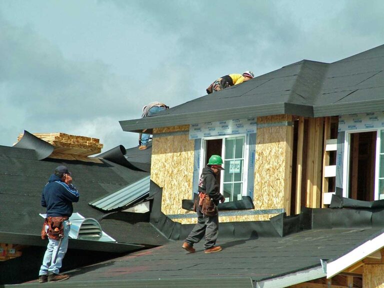 A close-up of a rooftop with asphalt shingles, partially covered by melting snow and ice.