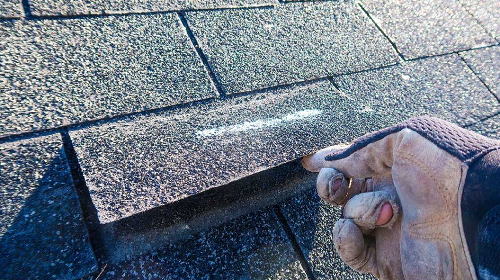 Close view of metal flashing around a chimney where shingles meet a sloped roof.