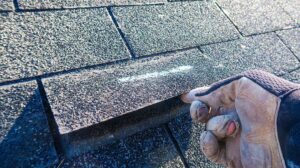 Close view of metal flashing around a chimney where shingles meet a sloped roof.
